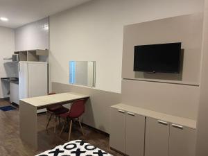 索罗卡巴Flat Aconchegante的厨房配有桌子,墙上配有电视。
