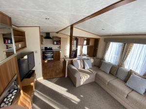 亨斯坦顿6 Berth Caravan With Decking At Manor Park In Hunstanton Ref 23017h的带沙发和电视的客厅