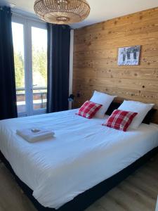SarcenasRésidence les 3 Sommets的卧室配有一张带两个红色枕头的大型白色床