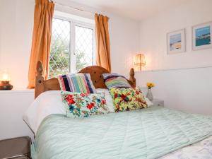 纽基Bro Tref Cottage的卧室配有带枕头的床铺和窗户。