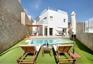 莫甘Escape to paradise luxury Poolvilla with ocieanview near Amadores的别墅 - 带游泳池、2把椅子和遮阳伞