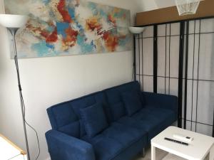 塞纳河畔勒梅Studio chez Virginie et Henri的客厅里一张蓝色的沙发,上面有绘画作品
