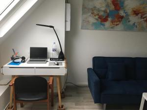 塞纳河畔勒梅Studio chez Virginie et Henri的一张桌子,上面有笔记本电脑,旁边是蓝色的沙发
