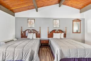 Highland Falls保尔武基西点军校旅馆及套房的配有白色墙壁和木制天花板的客房内的两张床