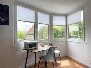 奥斯纳布吕克Zentral gelegene Studios I home2share的客房设有一张桌子、一台电脑和三扇窗户