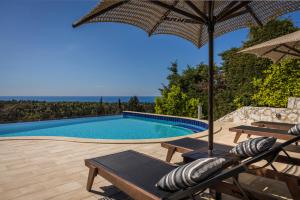 费斯卡尔德宏Luxury Villa Karmaniolos Fiskardo Kefalonia的一个带遮阳伞和椅子及桌子的游泳池