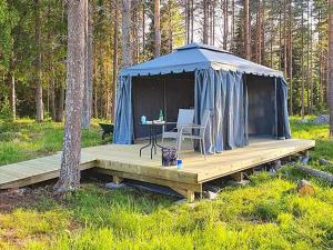 BureåHoliday home Bureå的蓝色帐篷,配有一张桌子和椅子,位于木制甲板上