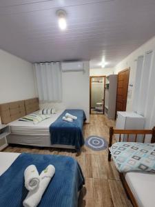 佩尼亚Pousada Pontal da Armação的小客房内的两张床,配有蓝色的床单