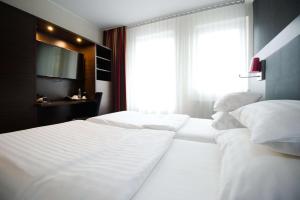 格拉茨Best Western Plus Plaza Hotel Graz的卧室设有2张白色的床和窗户。