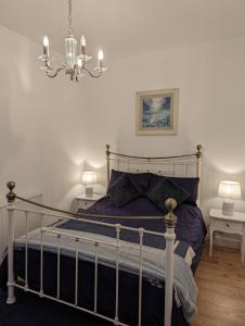 奈恩Shadow's Cottage situated in Fishertown, Nairn.的一间卧室配有一张带紫色床单和吊灯的床。