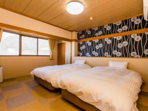 笛吹市Japanese Onsen Ryokan Kohakuen的一间卧室设有两张床和鲜花墙