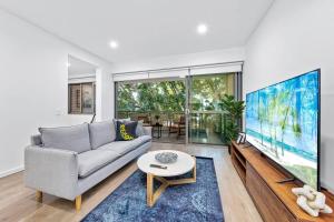 悉尼Centre of Newtown 2 Bed Apartment的带沙发和大屏幕电视的客厅