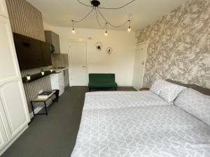 伦敦Cosy Bright Studio Apartment Close to Wembley Stadium的卧室配有白色的床和绿色椅子