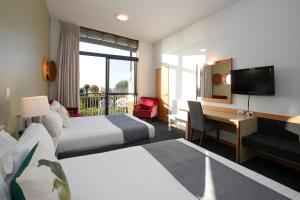 普纳凯基Scenic Hotel Punakaiki的酒店客房设有两张床、一张桌子和一台电视。