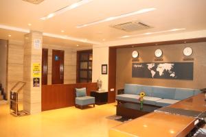 印多尔Kyriad Hotel Indore by OTHPL的一间设有蓝色沙发和墙上时钟的等候室