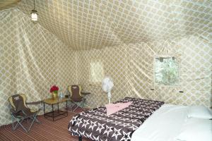穆克缇斯瓦FOREST ACRES CAMPS的卧室配有一张床和一张桌子及椅子