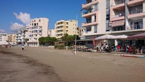 都拉斯Sunlit Coast Apartment Durrës的一片拥有建筑和坐在桌子上的海滩