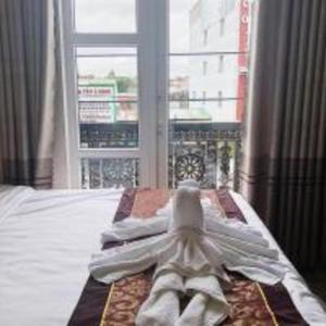 邦美蜀Kim Ngân Hotel Buôn Ma Thuột的窗户前的一张带白色毛巾的床