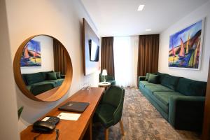 潘切沃Hotel Tamiš & Spa的带沙发、桌子和镜子的客厅