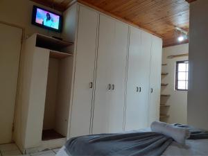 恩潘盖尼Kwesethu Guesthouse的卧室配有白色橱柜和墙上的电视。