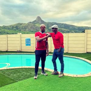 埃祖尔韦尼Mantenga Hillview的两个身穿红衬衫的人站在游泳池旁