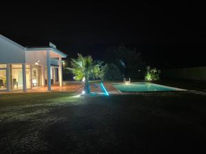 ParbayónVilla LA PERLA con piscina privada的夜间在房子前面的游泳池