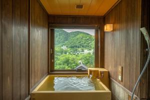 JozankeiJozankei Onsen Yurakusoan的窗户客房内的浴缸
