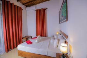 锡吉里亚Sigiri Asna Nature Resort的卧室配有白色的床和红色窗帘