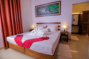 锡吉里亚Sigiri Asna Nature Resort的一间卧室配有一张大白色床,上面有红色的弓