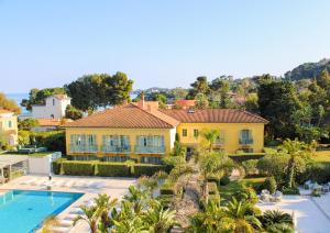 费拉角圣让Hotel Royal-Riviera的一座大型黄色房子,设有游泳池和棕榈树