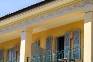 费拉角圣让Hotel Royal-Riviera的黄色的房屋,设有蓝色百叶窗和阳台