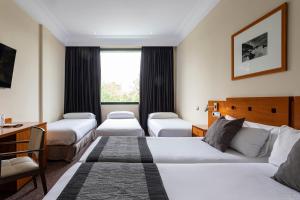 马德里珀蒂宫阿图罗索里亚阿尔卡拉酒店的酒店客房设有三张床和一张书桌