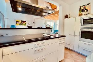 RoscanvelLes agapanthes - vue mer的厨房配有白色橱柜和炉灶烤箱。
