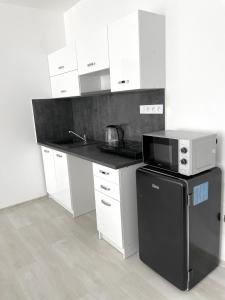 什图罗沃MG Apartments Štúrovo的厨房配有白色橱柜和黑微波炉