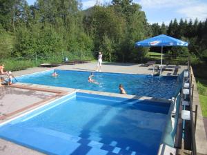 Morávka水坝酒店的一群人在带遮阳伞的游泳池里