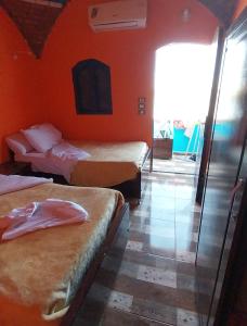 阿斯旺NeNeKaTo Nubian House的酒店客房设有两张床和橙色的墙壁。
