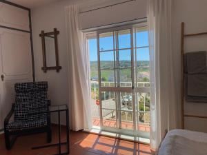 阿尔热祖尔Guesthouse Releash Aljezur的一间卧室设有窗户和椅子,享有美景
