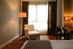 奥尔梅多Castilla Termal Olmedo的酒店客房配有一张床、一把椅子和一张书桌