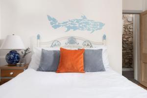 圣艾夫斯Saffron Cottage, St Ives的卧室配有白色床和橙色枕头