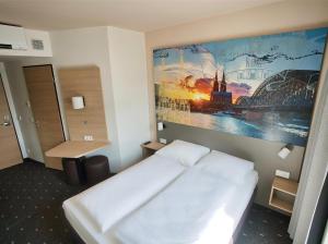 科隆B&B Hotel Köln-City的卧室配有白色的床和墙上的绘画作品