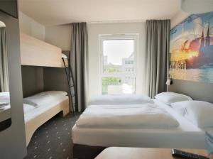 科隆B&B Hotel Köln-City的酒店客房设有三张床和窗户。