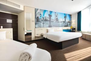 克拉科夫B&B HOTEL Krakow Centrum的酒店客房设有两张床,墙上挂有绘画作品