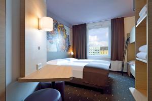 科隆B&B Hotel Köln-Ehrenfeld的配有一张床、一张书桌和一扇窗户的酒店客房