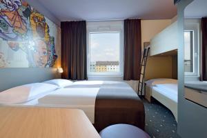 科隆B&B Hotel Köln-Ehrenfeld的酒店客房设有两张床和窗户。