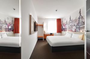 卢布林B&B Hotel Lublin Centrum的酒店客房设有两张床,墙上挂有绘画作品