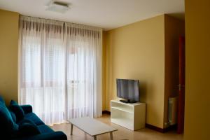 诺哈Playa Home Helgueras con acceso a Spa (AguaMarinaSpa)的客厅配有蓝色的沙发和电视