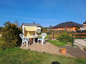 加兹尤瑟多姆Ferienwohnung Riemer的庭院设有两把椅子和一张桌子,还有一间狗屋。