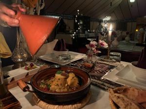 梅尔祖卡Merzouga Luxury Tented Camp的一个人在吃一碗食物中喝一杯