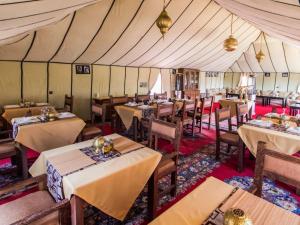 梅尔祖卡Merzouga Luxury Tented Camp的帐篷内带桌椅的餐厅
