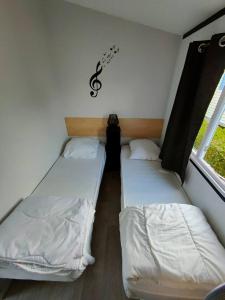 Biville-sur-MerLe Cocooning的一张小房间内的两张床,墙上挂着一美元标志